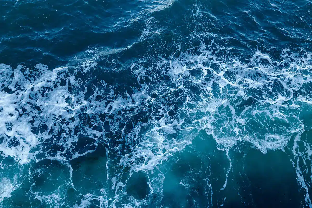 Aerial view of turbulent North Sea waves and white surf, representing the Dutch offshore waters through which the Tarchon interconnector cable will pass